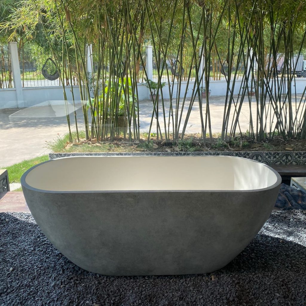 Bồn tắm DR13C với kiểu dáng oval đơn giản, đặt ngoài trời trên nền đá sỏi, hài hòa cùng không gian cây trúc xanh.